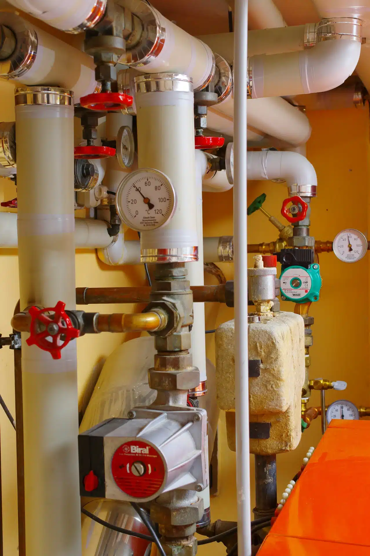 complex industrial heating installation featuring Biral and Wilo circulating pumps, insulated pipework, red handled gate valves, and temperature gauges.